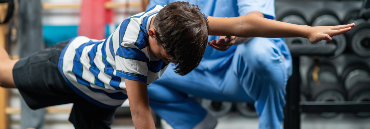 Physical therapist guiding a young boy through exercises for stability and balance